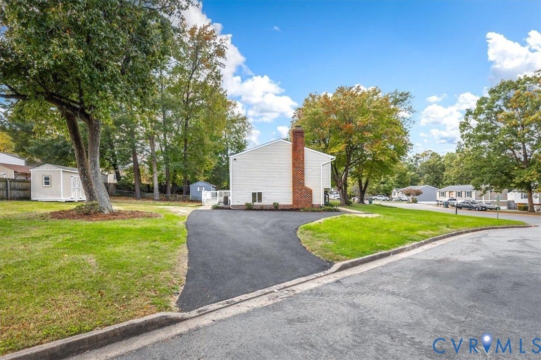 9201 Packard Court, Glen Allen, VA 23060 Exterior featuring light-colored horizontal siding, an exposed brick chimney, an asphalt driveway, and a detached storage structure on a grass-covered lot