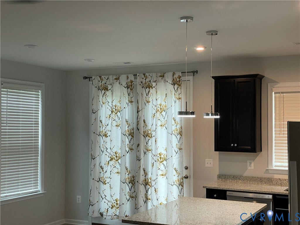 9212 St Charles Circle, Richmond, VA 23235 Kitchen featuring dark-finish cabinetry, stone-texture countertops, dual modern pendant lighting, and horizontal slatted window blinds