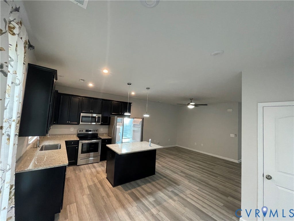 9212 St Charles Circle, Richmond, VA 23235 Kitchen featuring dark cabinetry, stone-finish countertops, stainless steel appliances, a center island with dual pendant lighting, and wood-finish flooring