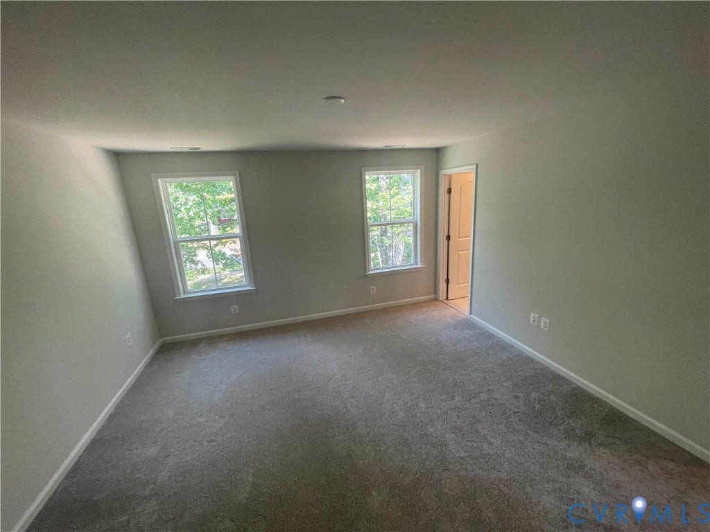 9212 St Charles Circle, Richmond, VA 23235 Room featuring neutral-toned carpeting, two double-hung windows, and a traditional six-panel interior door