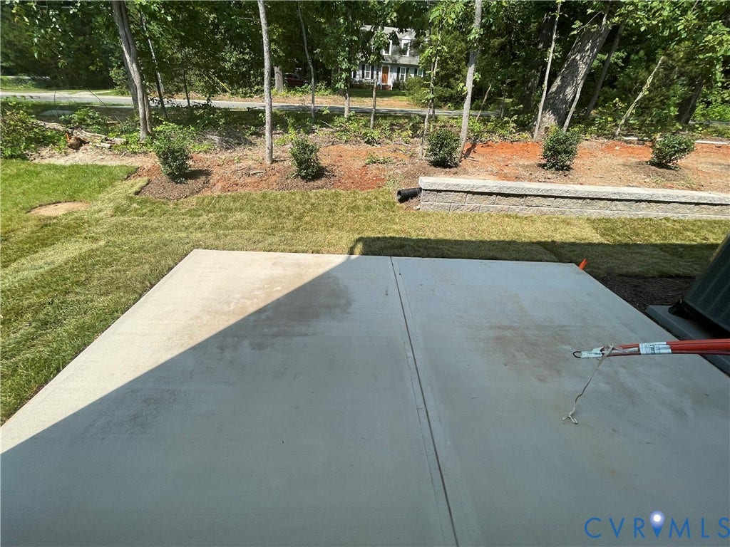 9212 St Charles Circle, Richmond, VA 23235 Concrete patio featuring a low-profile stone retaining wall and grass lawn
