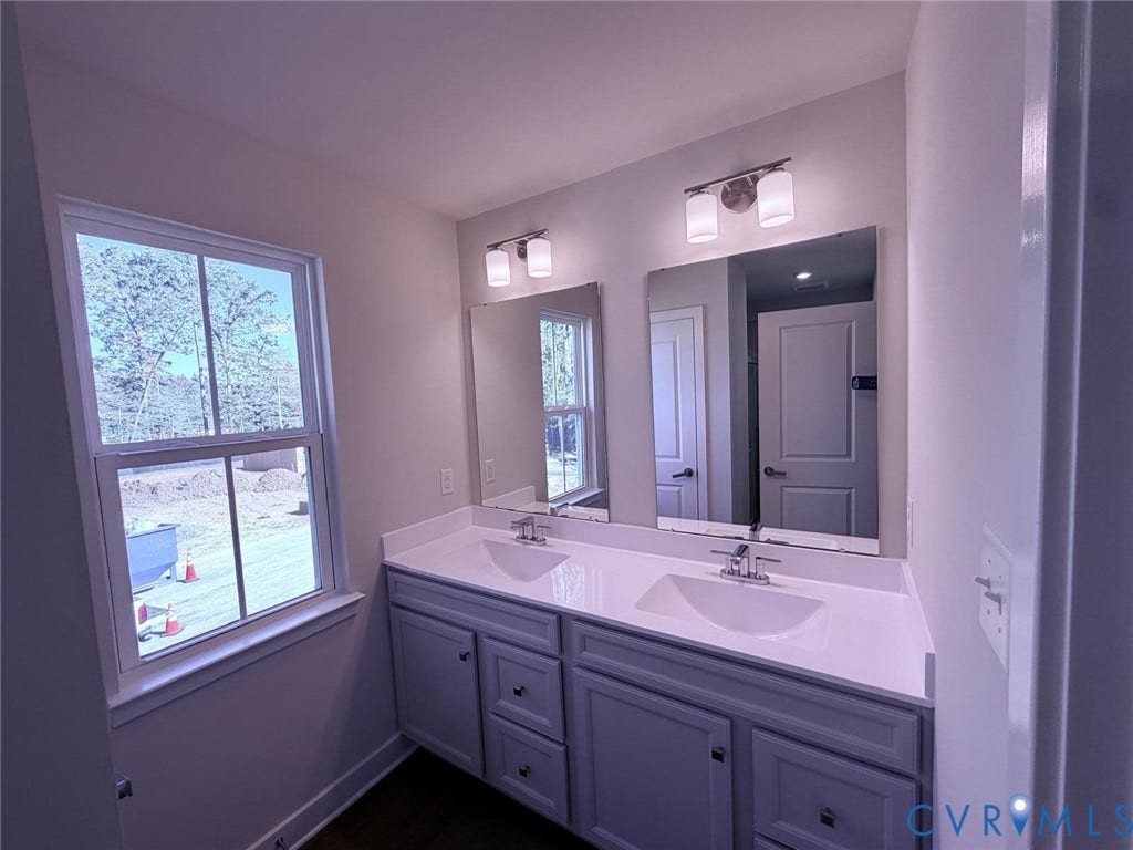 10600 Pink lily Lane, Chesterfield, VA 23234 Double vanity featuring a stone countertop, dual integrated rectangular sinks, polished chrome fixtures, and shaker-style cabinetry with dual wall-mounted light fixtures