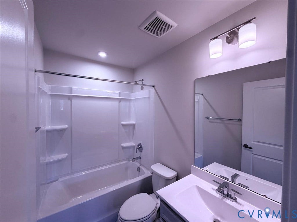 10600 Pink lily Lane, Chesterfield, VA 23234 Bathroom featuring a tub and shower combination with integrated shelving, a rectangular vanity with a solid-surface countertop, a large wall-mounted mirror, and dual-light fixture