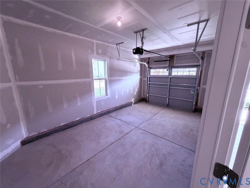 10600 Pink lily Lane, Chesterfield, VA 23234 Interior garage space featuring concrete flooring, unpainted gypsum wallboard, a single-pane window, and an automated overhead door opener