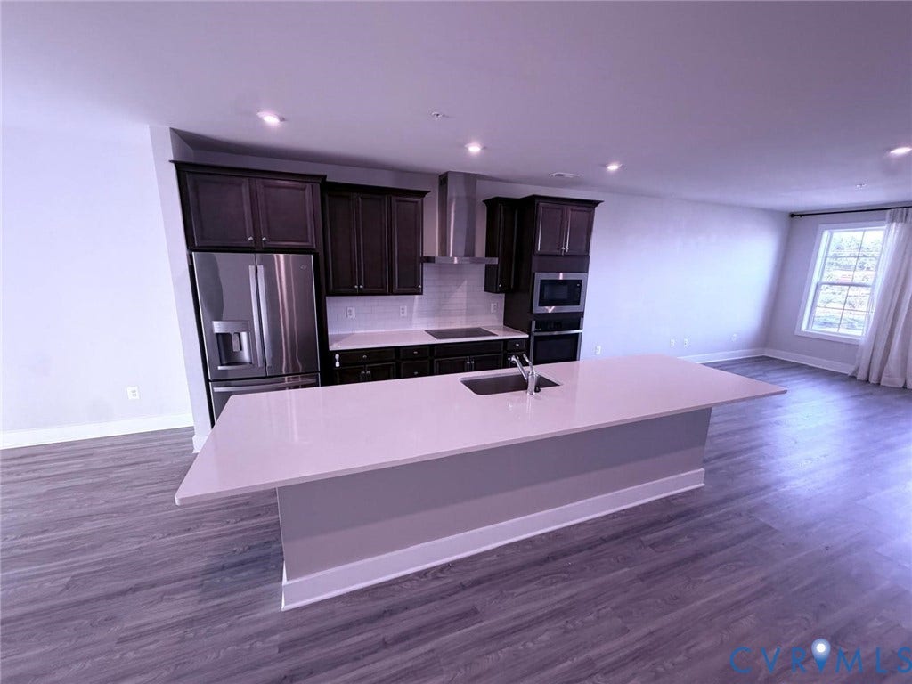 4411 GREYBULL Walk, #B, Glen Allen, VA 23233 Kitchen featuring dark-finish cabinetry, stone-surface countertops, stainless steel appliances, a center island with an undermount sink, and wood-finish flooring