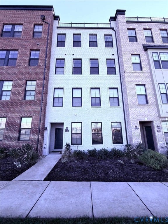 4411 GREYBULL Walk, #B, Glen Allen, VA 23233 Four-story brick townhouse exterior featuring a rooftop terrace, dark-framed windows, and a dedicated concrete walkway