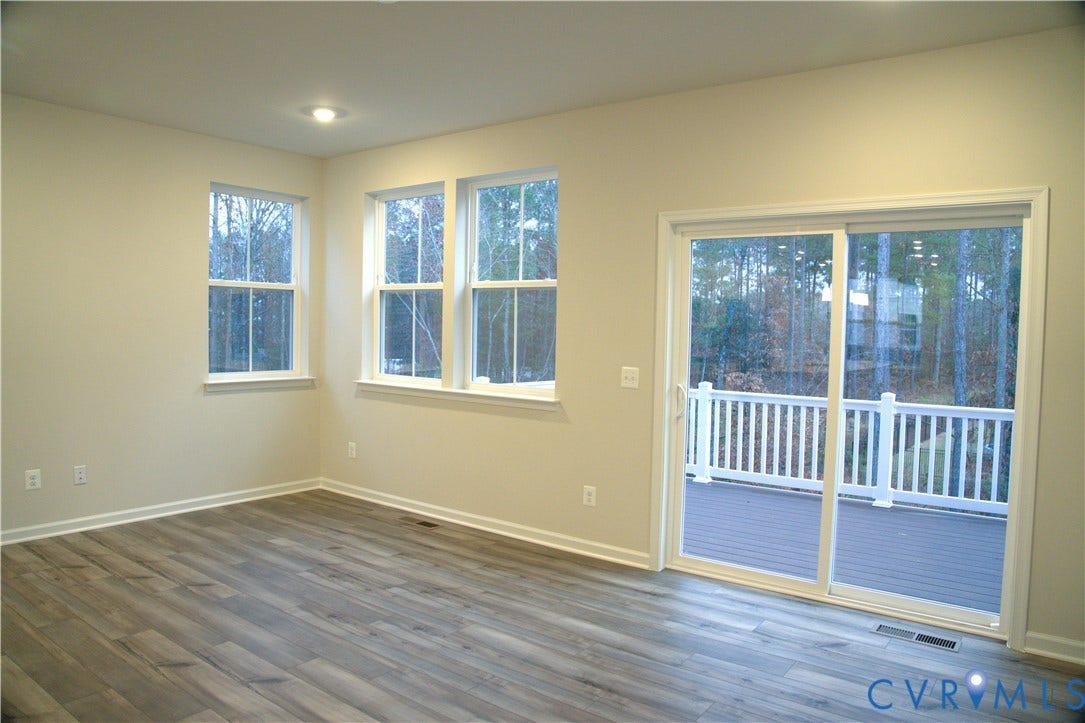 16005 Abelson Way, Chesterfield, VA 23832 Neutral-toned interior featuring wood-finish flooring, multi-pane windows, recessed lighting, and a sliding glass door providing access to a deck with a white balustrade