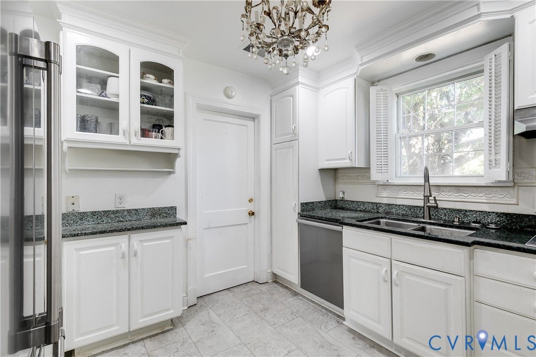 1406 Wentbridge Road, Richmond, VA 23227 Kitchen featuring white cabinetry with glass-front display uppers, dark stone countertops, stainless steel undermount sink, ceramic tile flooring, and a tiered crystal chandelier