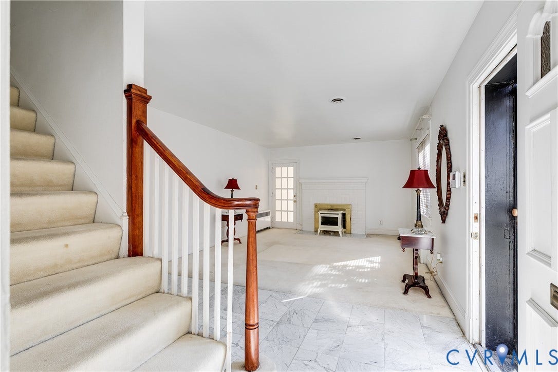 1406 Wentbridge Road, Richmond, VA 23227 Entryway featuring stone-finish tile flooring, a staircase with a stained wood handrail, white spindle balusters, and a fireplace with a masonry hearth