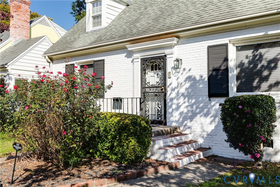 1406 Wentbridge Road, Richmond, VA 23227 White brick exterior featuring dark shutters, a front dormer window, metal decorative storm door, and masonry steps