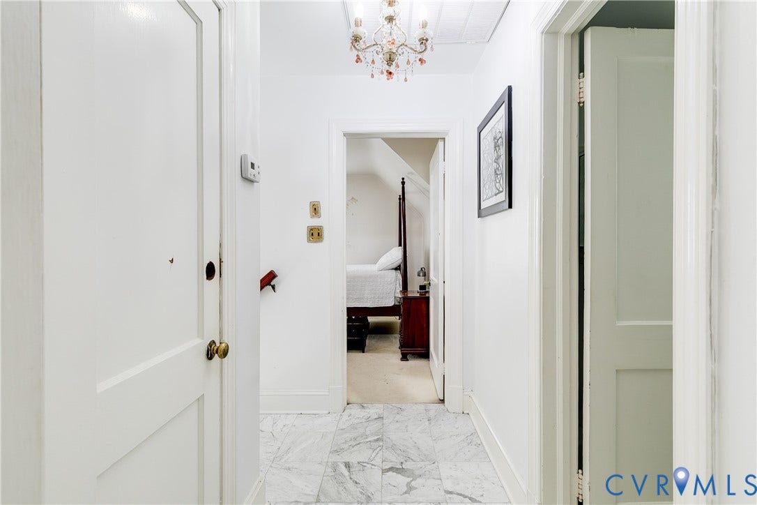 1406 Wentbridge Road, Richmond, VA 23227 Hallway featuring stone flooring, a tiered crystal chandelier, and paneled interior doors with brass-tone hardware