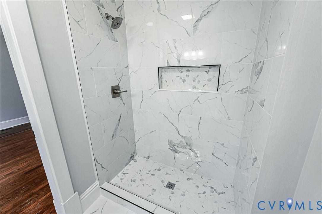 710 La Von Drive, Henrico, VA 23227 Walk-in shower featuring large-format tile surround with a veined pattern, built-in recessed wall niche, brushed-finish fixtures, and a coordinating tiled floor