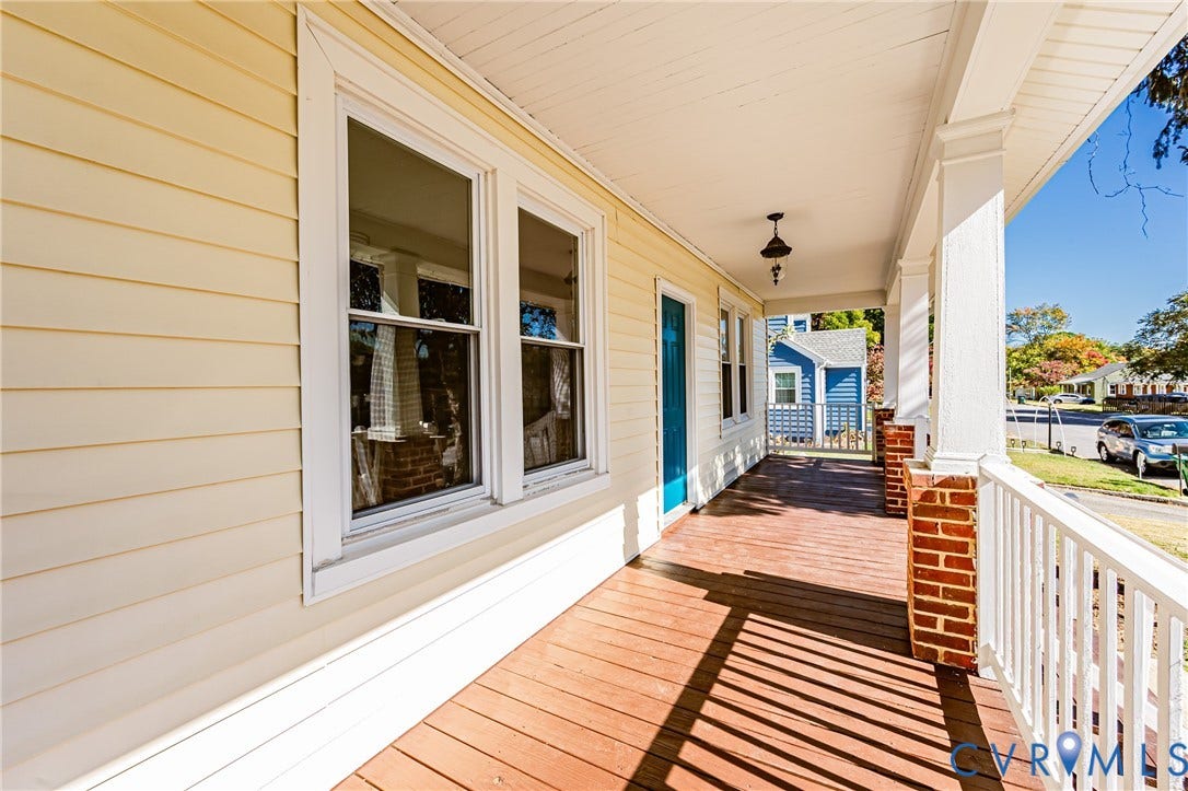 710 La Von Drive, Henrico, VA 23227 Covered porch featuring wood-finish decking, white railings, brick-based columns, and a single-light exterior pendant fixture