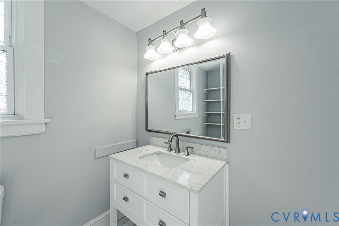710 La Von Drive, Henrico, VA 23227 White vanity with a stone countertop, undermount sink, metal faucet, framed mirror, and four-light vanity fixture