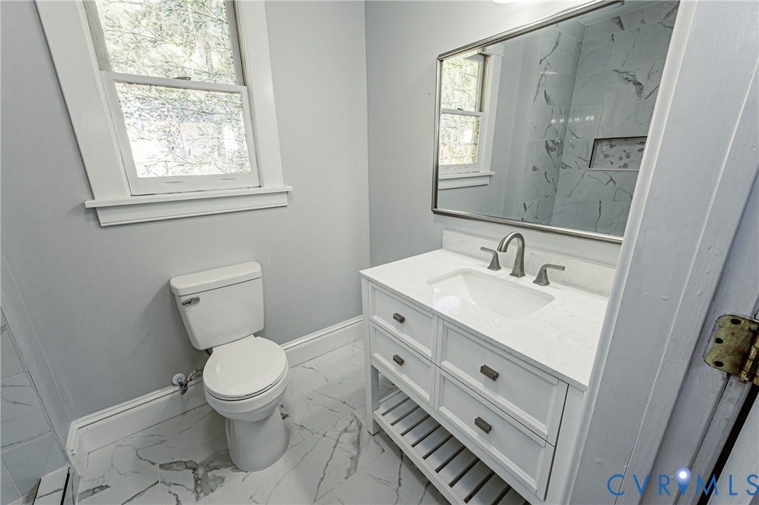 710 La Von Drive, Henrico, VA 23227 Bathroom featuring a vanity with a white composite countertop, undermount sink, brushed nickel faucet, large wall-mounted mirror, and stone-finish floor tile
