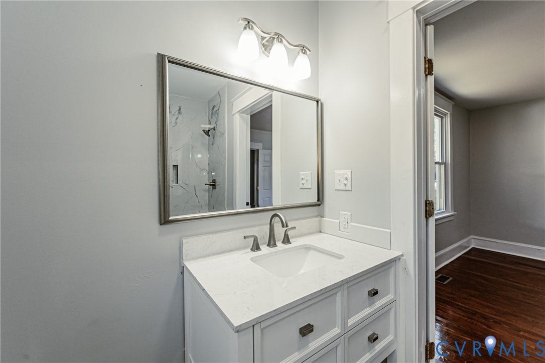 710 La Von Drive, Henrico, VA 23227 White cabinetry with a stone countertop, integrated sink, framed rectangular mirror, and three-light fixture