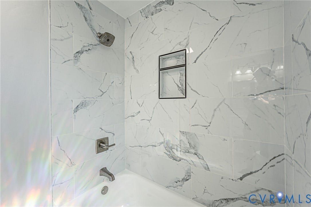 710 La Von Drive, Henrico, VA 23227 Bathtub surround featuring large-format veined tile, brushed metal fixtures, and a recessed built-in shower niche