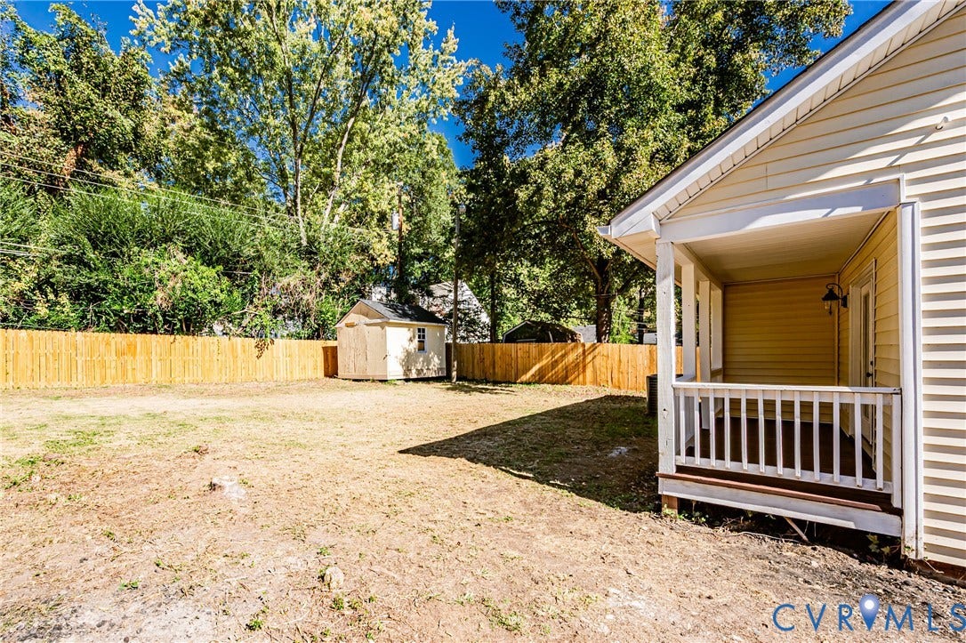 710 La Von Drive, Henrico, VA 23227 Rear exterior featuring a covered porch with white railing, a wood-slat privacy fence, and a detached storage shed