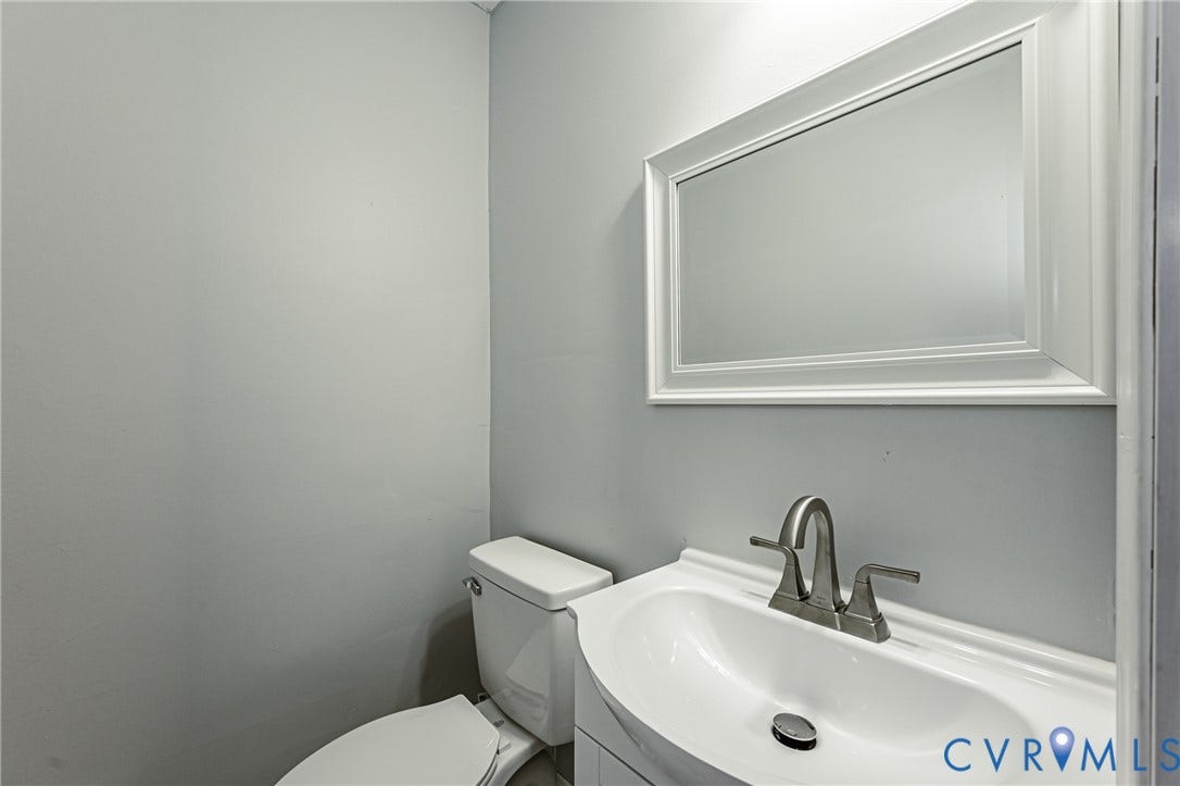 710 La Von Drive, Henrico, VA 23227 Vanity featuring an integrated white sink, brushed nickel dual-handle faucet, rectangular framed wall mirror, and porcelain toilet