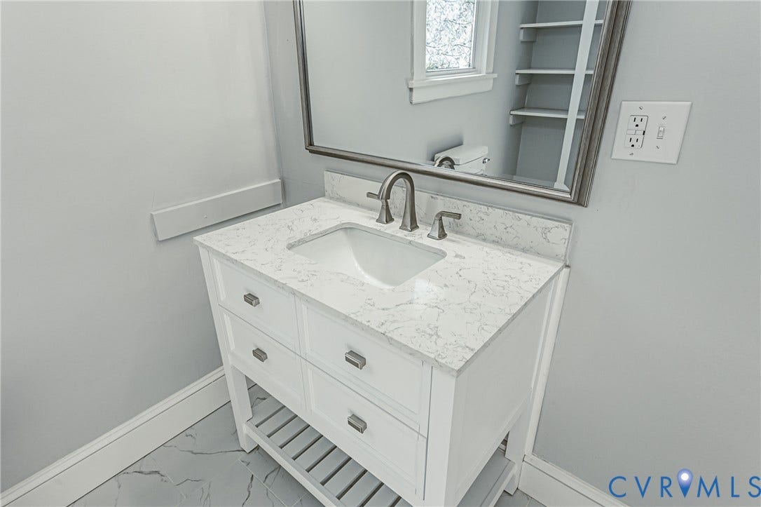 710 La Von Drive, Henrico, VA 23227 White vanity featuring a stone-composite countertop, undermount sink, metallic faucet, integrated lower shelving, and a framed mirror