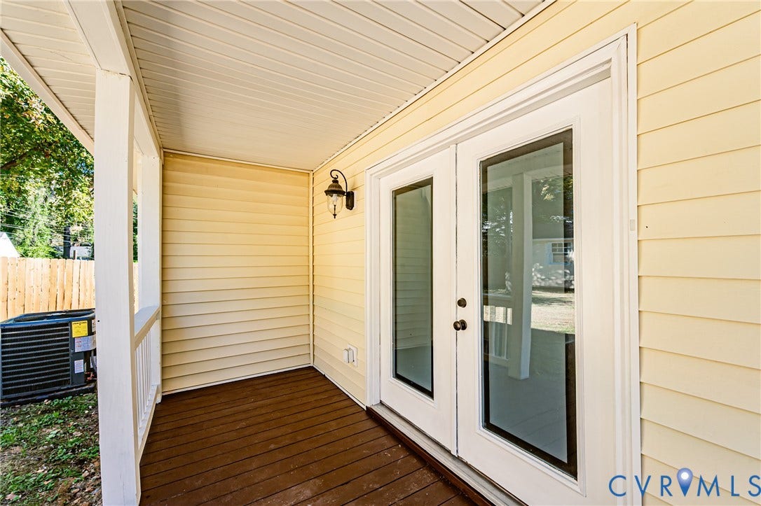 710 La Von Drive, Henrico, VA 23227 Covered porch with wood-finish decking, light-colored horizontal siding, dual glass-panel entry doors, and wall-mounted exterior light fixture