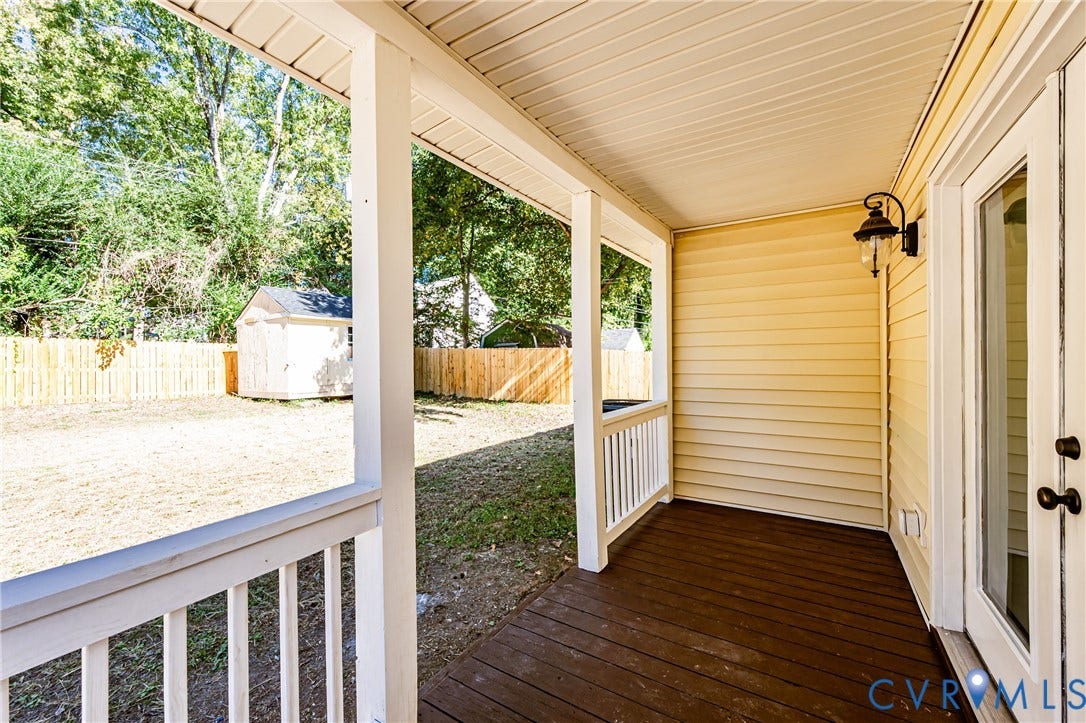 710 La Von Drive, Henrico, VA 23227 Covered porch with wood-finish decking, white baluster railing, wall-mounted exterior light fixture, and vinyl siding