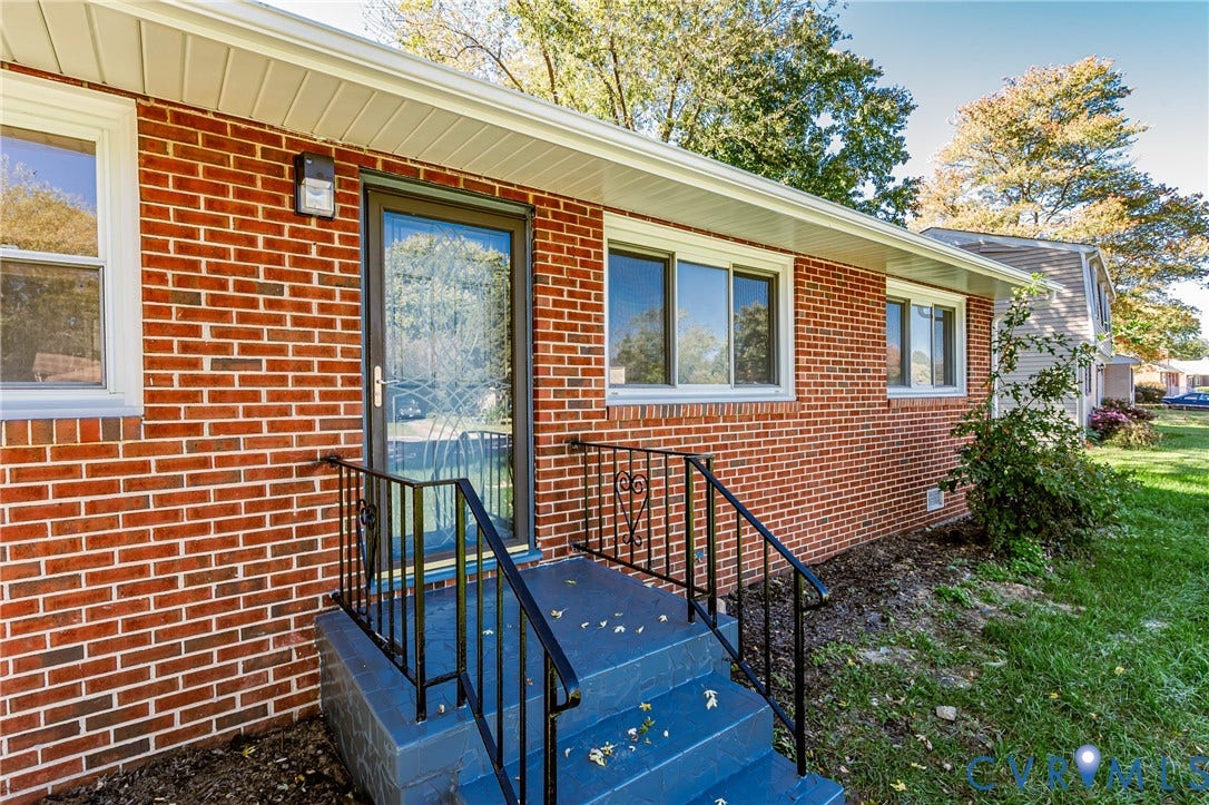 506 Meadowspring Road, Henrico, VA 23223 Red brick exterior featuring painted concrete stairs, black metal railings, a storm door with glass detailing, and vinyl window frames