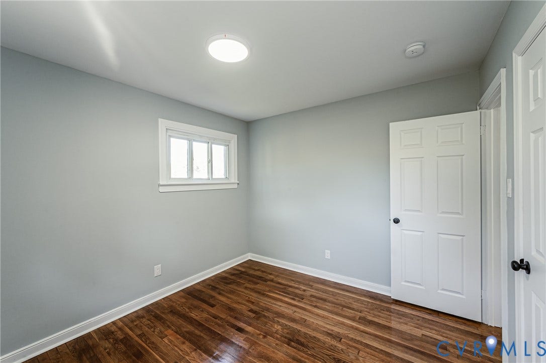 506 Meadowspring Road, Henrico, VA 23223 Room featuring wood-finish flooring, neutral wall paint, a six-panel door with matte black hardware, and a single-hung window with white casing