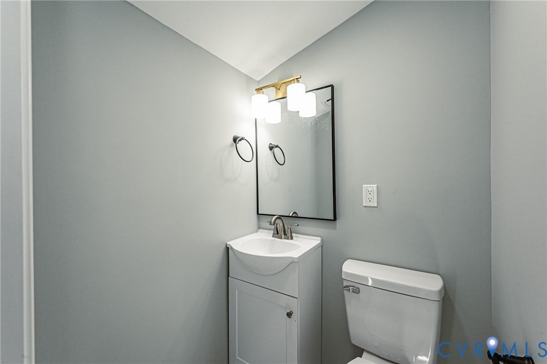 506 Meadowspring Road, Henrico, VA 23223 Pedestal-style vanity with integrated sink, rectangular wall mirror with black frame, three-light vanity fixture with globe shades, and polished metal hardware