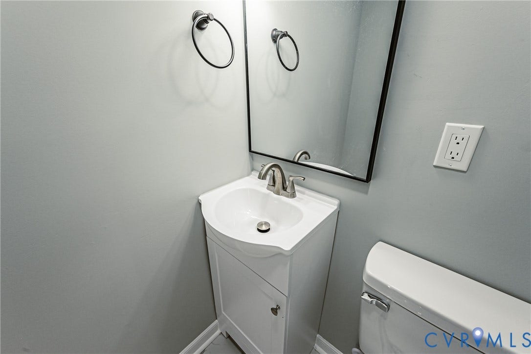 506 Meadowspring Road, Henrico, VA 23223 Pedestal vanity with white cabinetry and integrated basin, chrome finish faucet, black-framed mirror, and circular towel ring