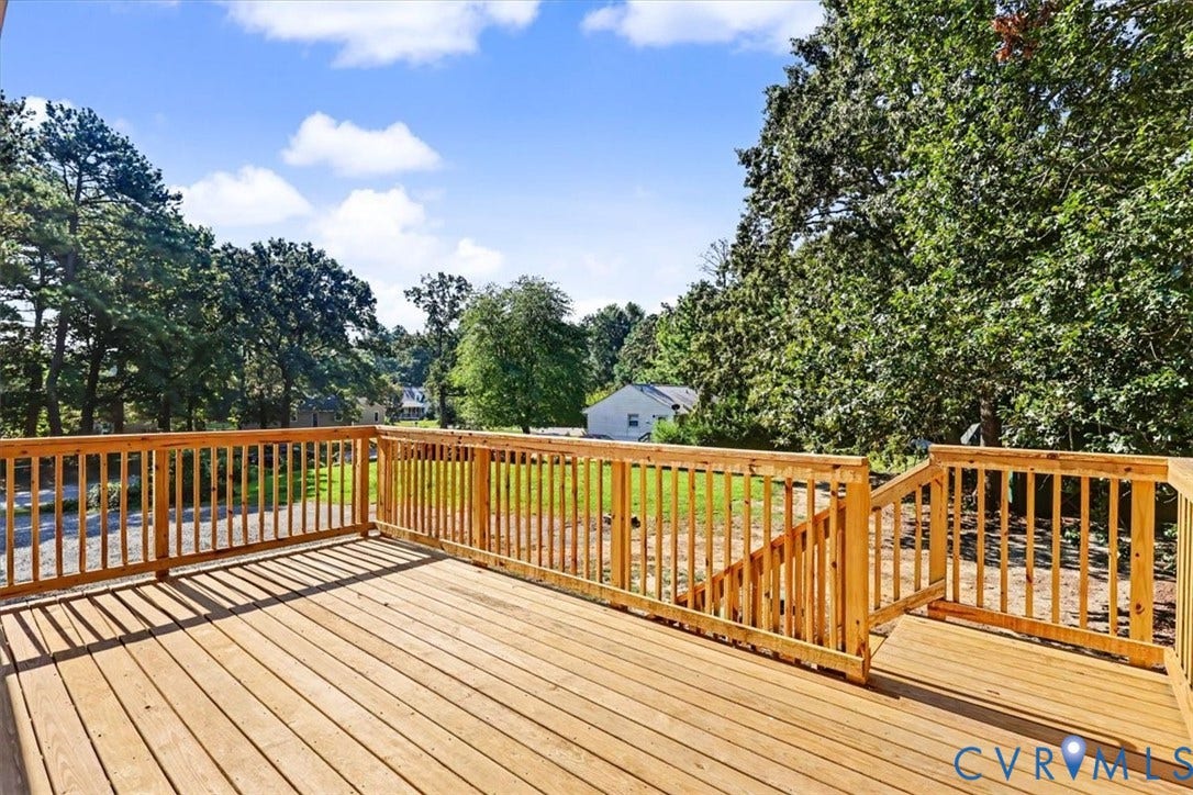 9737 Graves Road, South Chesterfield, VA 23803 Elevated wood deck featuring vertical wood balusters and stairs leading to the grounds, complemented by mature trees