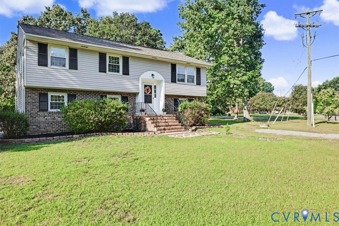 9737 Graves Road, South Chesterfield, VA 23803 Split-level exterior featuring brick and horizontal siding, arched entryway, brick-stepped stairs with metal railings, and multi-pane windows with decorative shutters