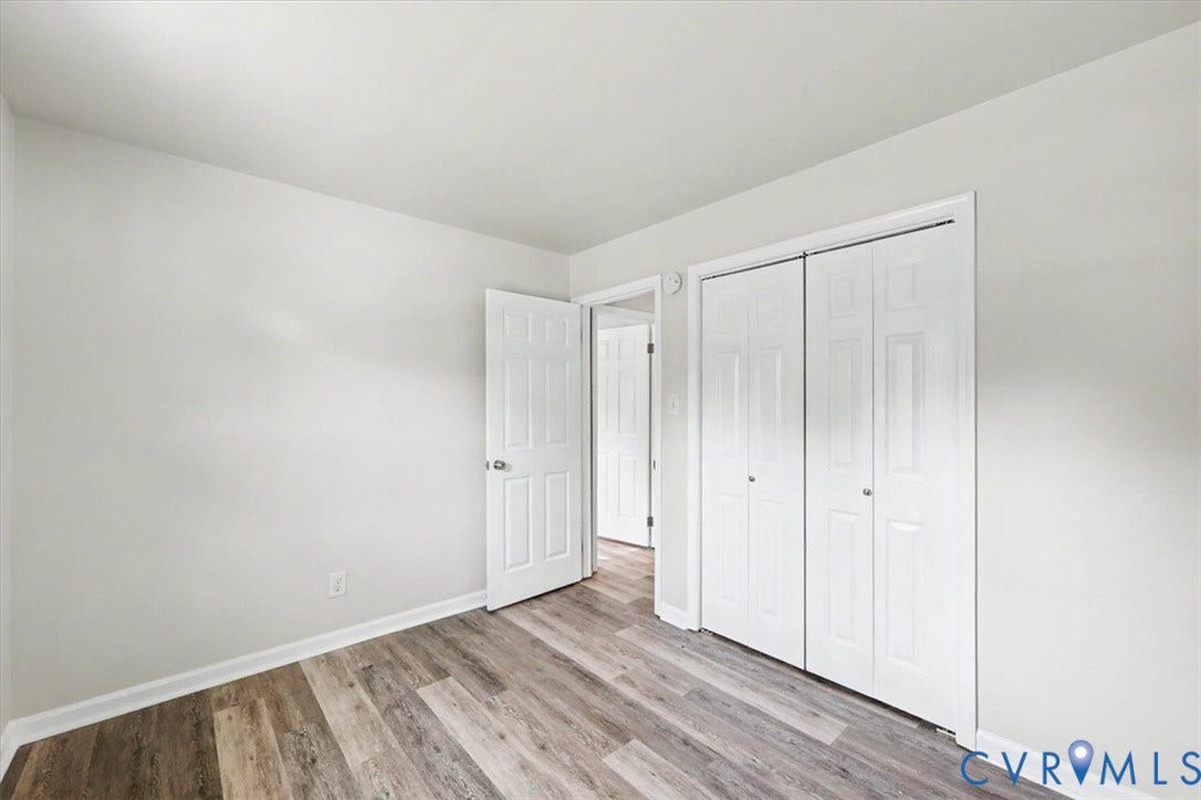 9737 Graves Road, South Chesterfield, VA 23803 Neutral-toned interior space featuring wood-finish flooring, dual-panel interior doors, and a double-door closet with paneled detailing