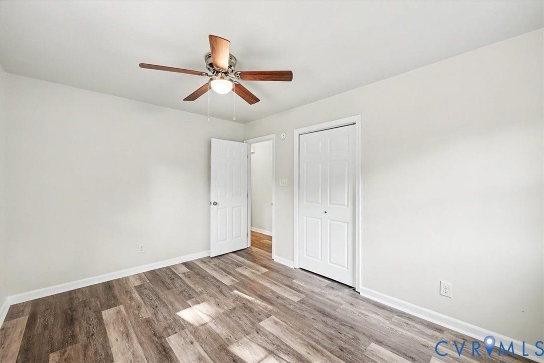 9737 Graves Road, South Chesterfield, VA 23803 Neutral walls paired with wood-finish flooring, featuring a ceiling-mounted light fixture with fan, six-panel interior door, and double-door closet