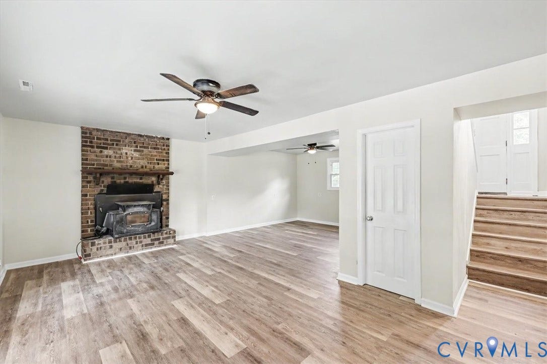 9737 Graves Road, South Chesterfield, VA 23803 Living area featuring wood-finish flooring, a floor-to-ceiling brick fireplace with a wood mantel, a ceiling fan, and a staircase with wood treads