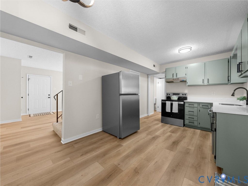 406 Alamosa Drive, Henrico, VA 23075 Kitchen featuring wood-finish flooring, stainless steel appliances, light-toned cabinetry, and solid-surface countertops