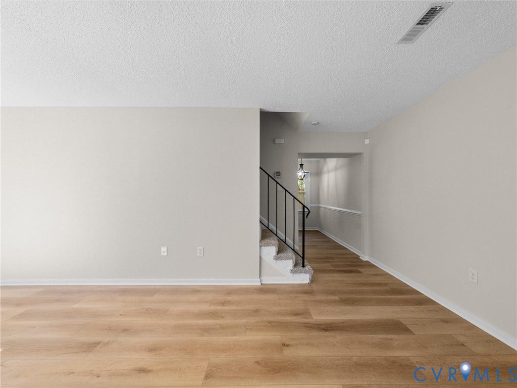 406 Alamosa Drive, Henrico, VA 23075 Neutral-toned interior featuring wood-finish flooring, staircase with metal railing, and textured ceiling