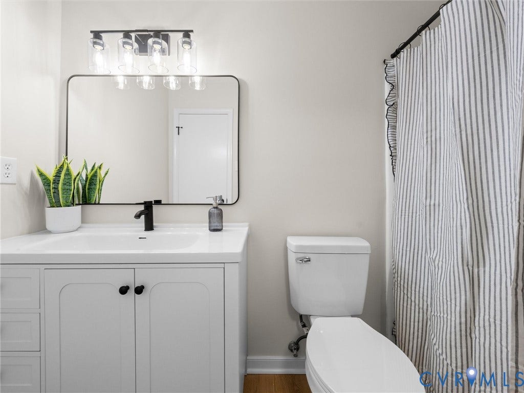 406 Alamosa Drive, Henrico, VA 23075 White vanity featuring a rectangular integrated sink, matte black faucet, rounded rectangular mirror, and multi-bulb industrial light fixture