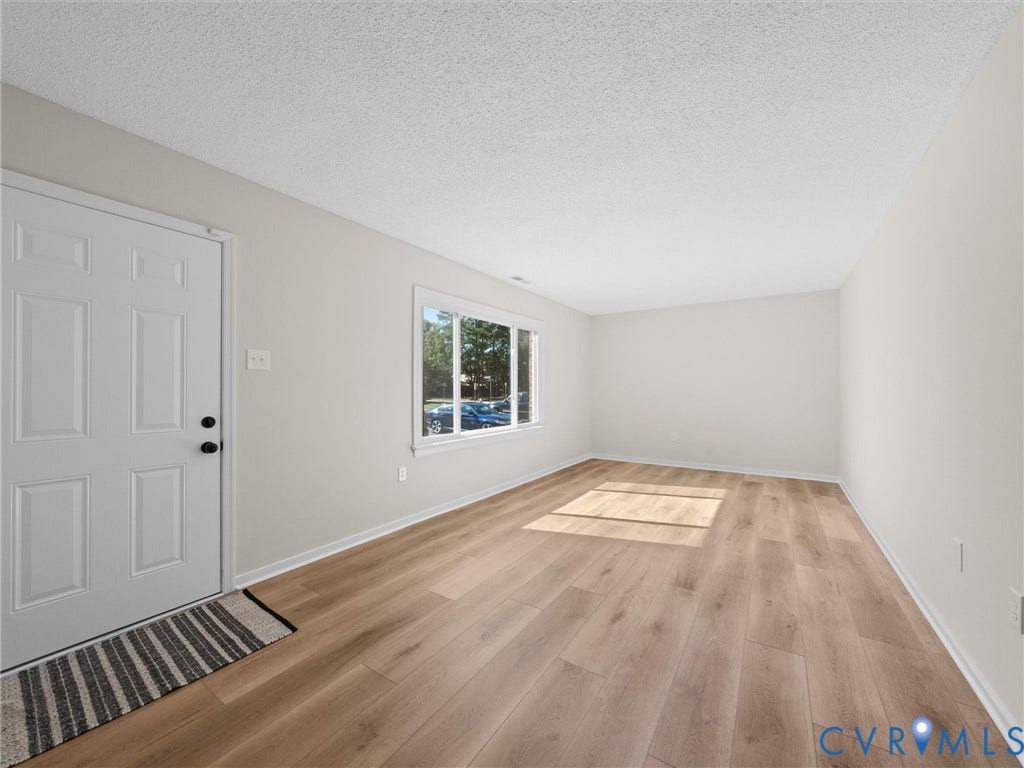 406 Alamosa Drive, Henrico, VA 23075 Neutral-toned interior space featuring light wood-finish flooring, a six-panel exterior entry door, and a large single-pane window with white trim
