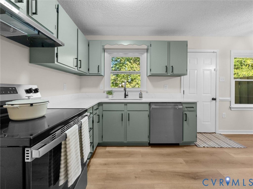 406 Alamosa Drive, Henrico, VA 23075 Kitchen featuring light-toned cabinetry with dark hardware, solid-surface countertops, wood-finish flooring, and stainless steel appliances