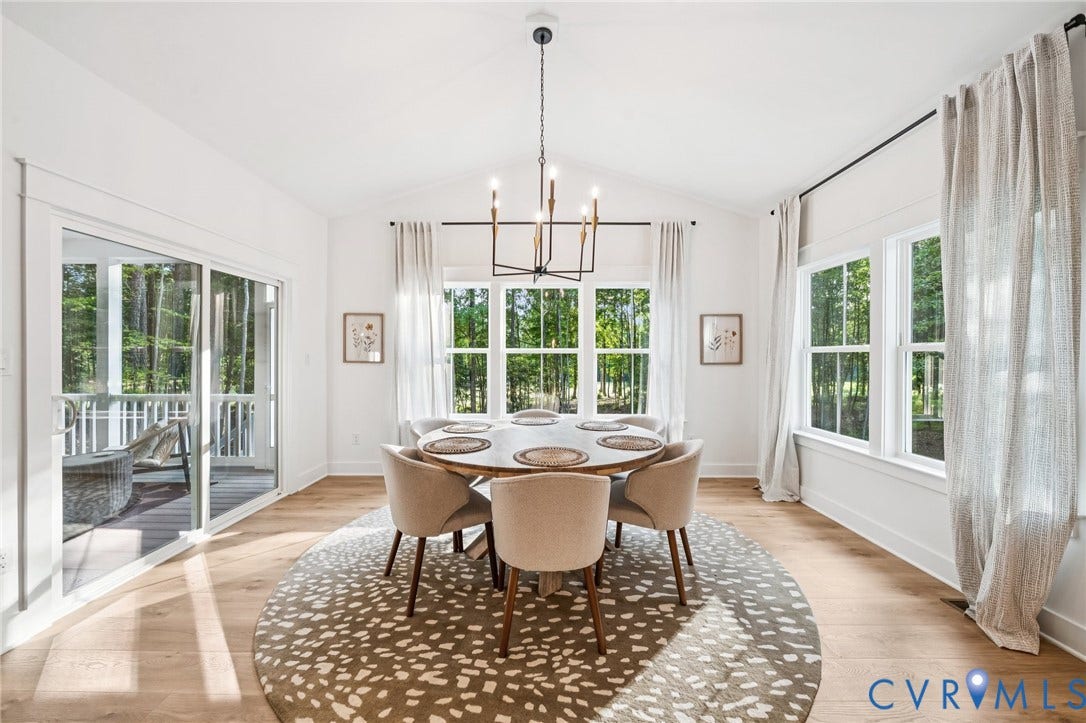 9156 Terroir Lane, The Viniterrta Villas, New Kent, VA 23124 Vaulted ceilings, wood-finish flooring, multi-pane windows, a linear metal chandelier, and a sliding glass door