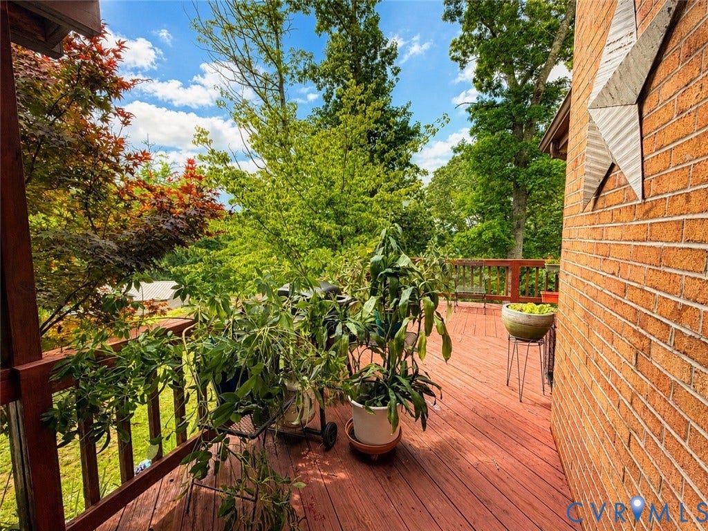 65 Cubbley Road, Hot Springs, VA 24445 Spacious outdoor deck with wood-finish decking, anchored by a brick exterior wall and surrounding mature trees