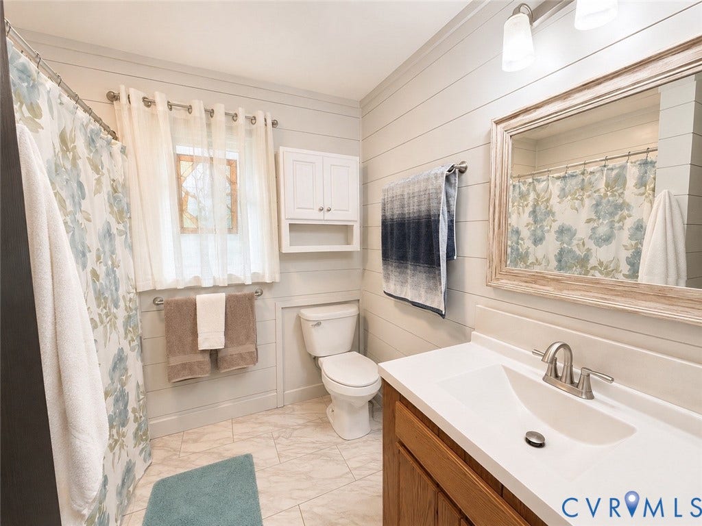 65 Cubbley Road, Hot Springs, VA 24445 Bathroom featuring horizontal shiplap wall paneling, vanity with an integrated countertop and basin, wall-mounted cabinetry, polished metal faucet, and multi-tone tiled flooring