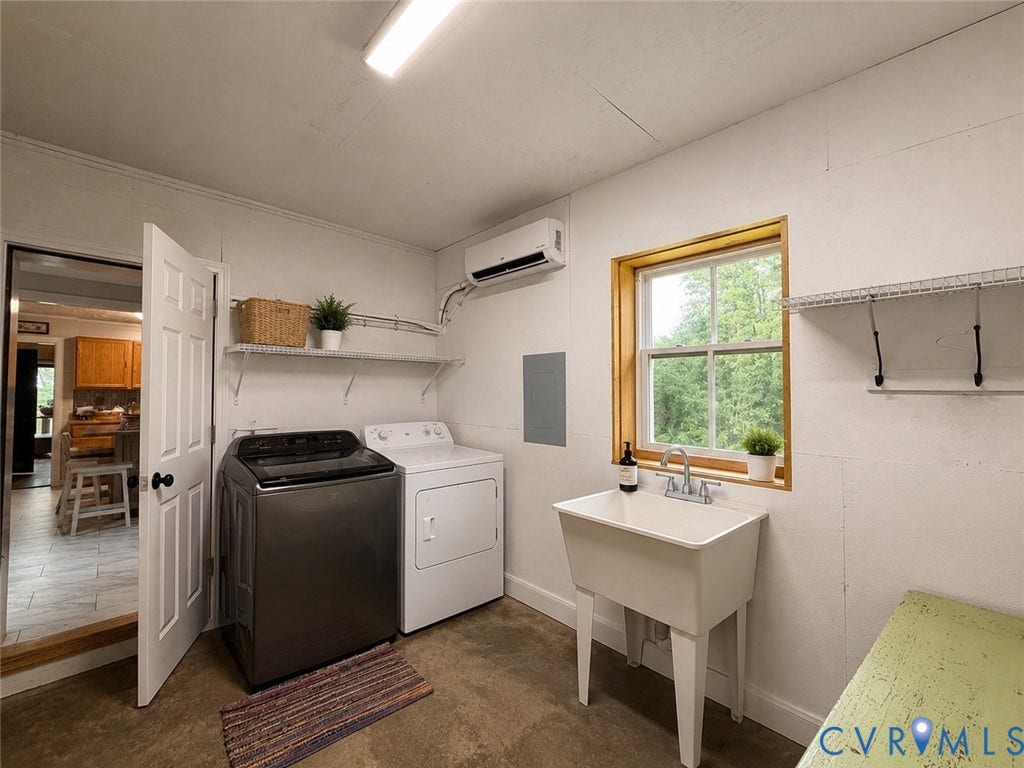 65 Cubbley Road, Hot Springs, VA 24445 Laundry area featuring a utility sink with dual-handle faucet, wall-mounted ductless air conditioning unit, window with natural wood trim, and metal shelving
