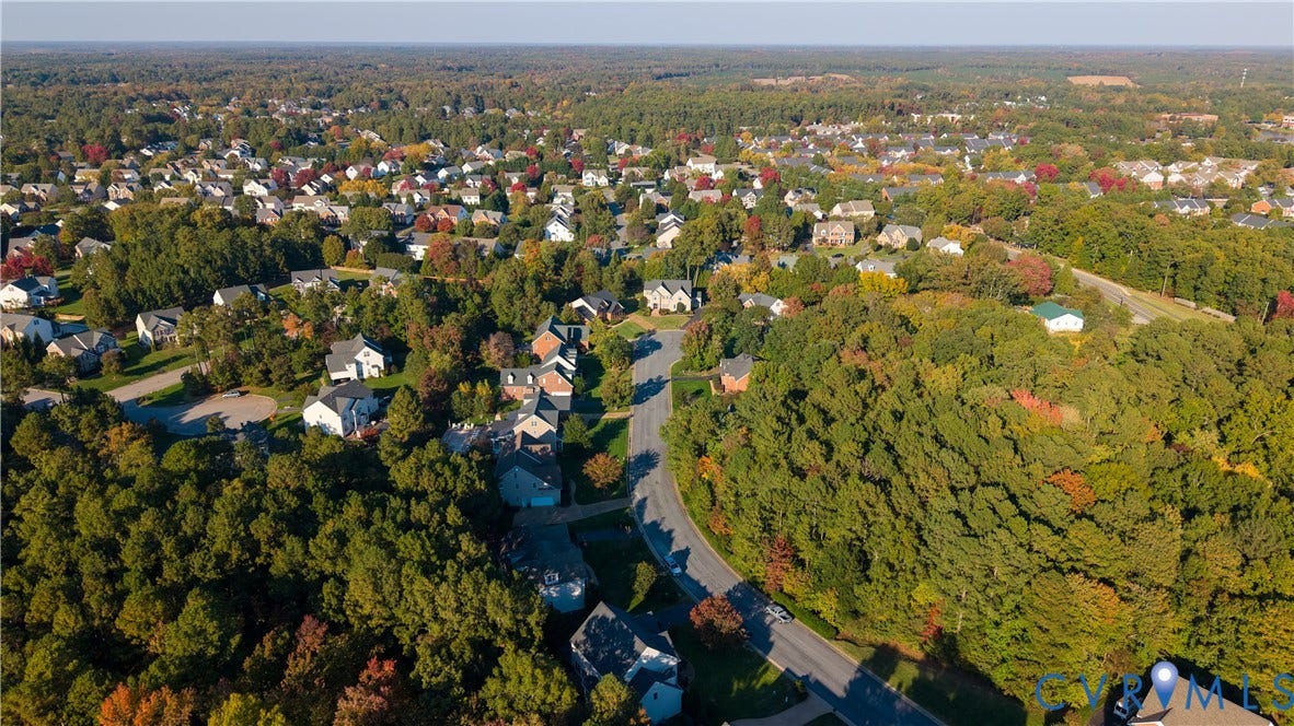 Aerial perspective of a suburban neighborhood featuring winding paved streets and extensive mature tree canopy