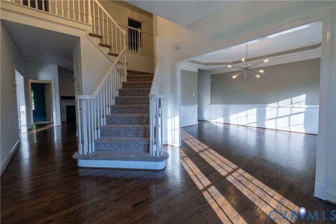 Foyer featuring wood-finish flooring, a staircase with white balusters, multi-arm sputnik chandelier, crown molding, and wainscoting