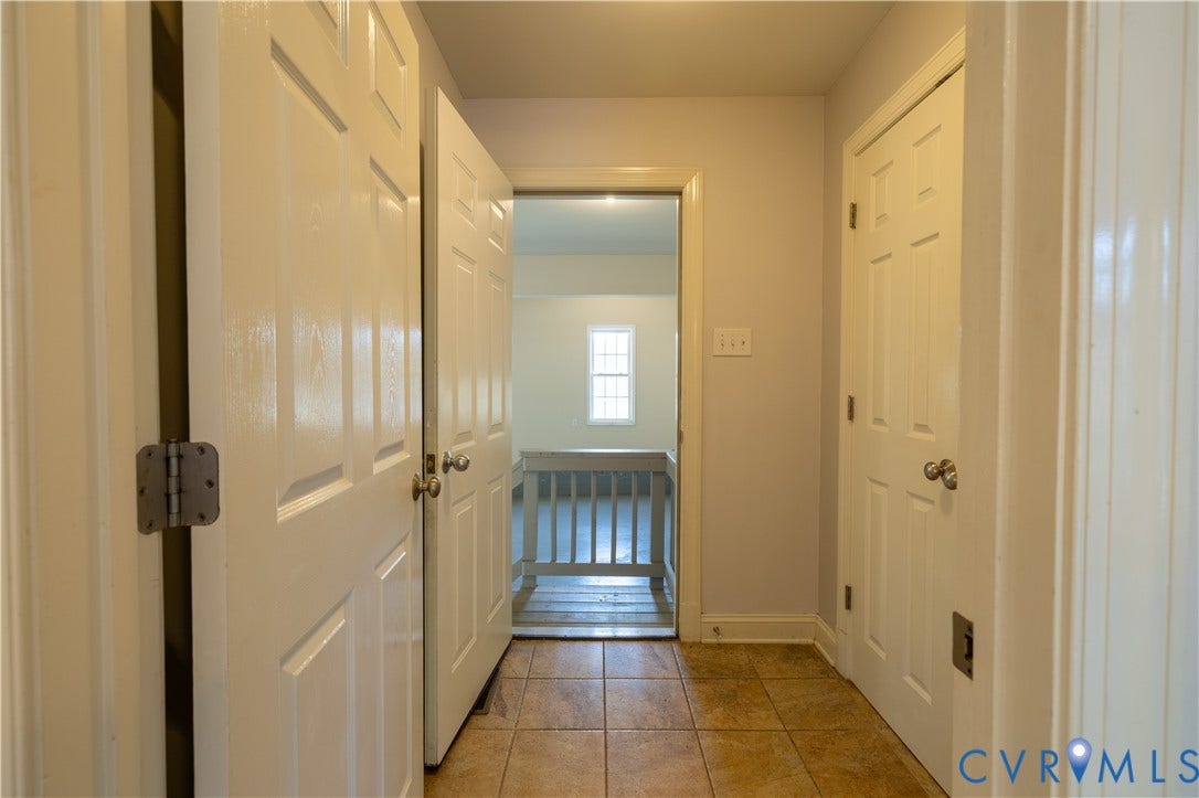 Interior space featuring tile flooring, six-panel solid core doors, and a railed staircase partition
