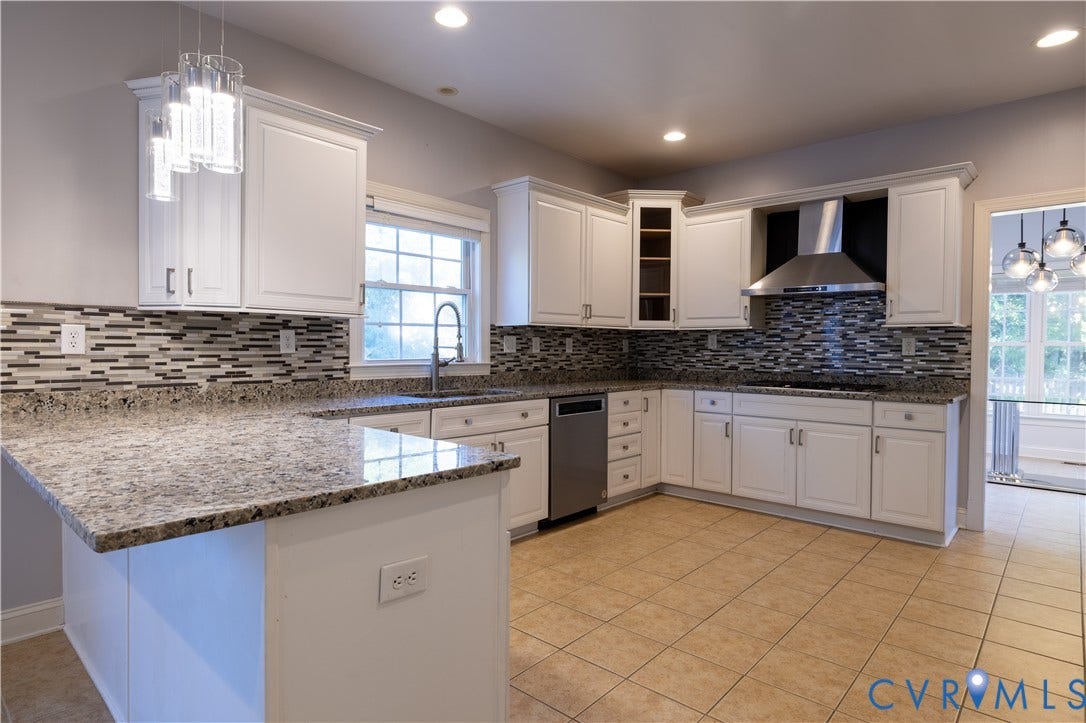 Kitchen featuring white cabinetry, stone countertops, multi-toned horizontal tile backsplash, stainless steel range hood, and pendant lighting