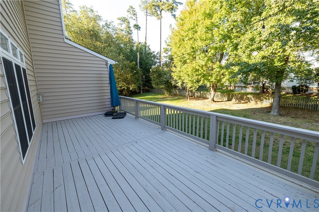 Spacious elevated deck featuring horizontal slat railing, neutral-toned plank decking, vinyl siding, and string lighting