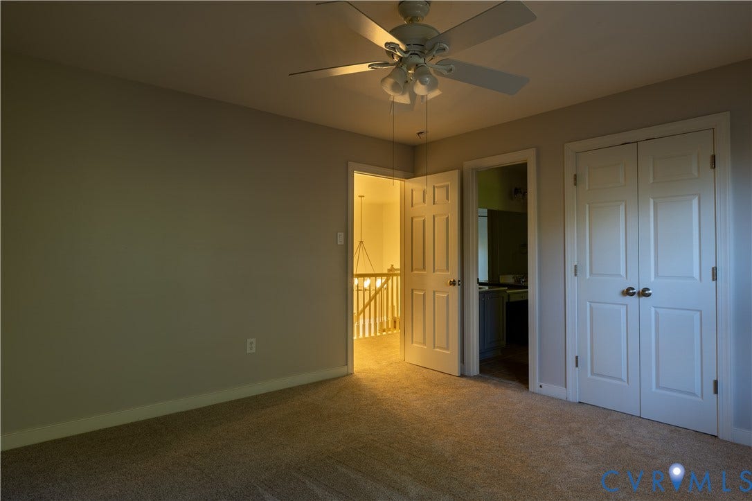 Interior space featuring neutral wall tones, wall-to-wall carpeting, ceiling fan with integrated lighting, and a double-door closet